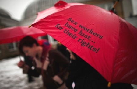 A woman holds a red umbrella, which are used as a symbol for sex workers’ rights, during a rally in Toronto on Friday. The Supreme Court of Canada struck down the country’s prostitution laws in a unanimous ruling, giving Parliament a year to produce new legislation
