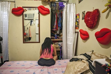 A prostitute sits in her room at a Blue House brothel in Puerto Cabello. Prostitutes more than double their earnings by moonlighting as currency traders for sailors.