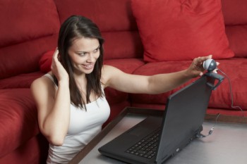 Young woman adjusting webcam on laptop